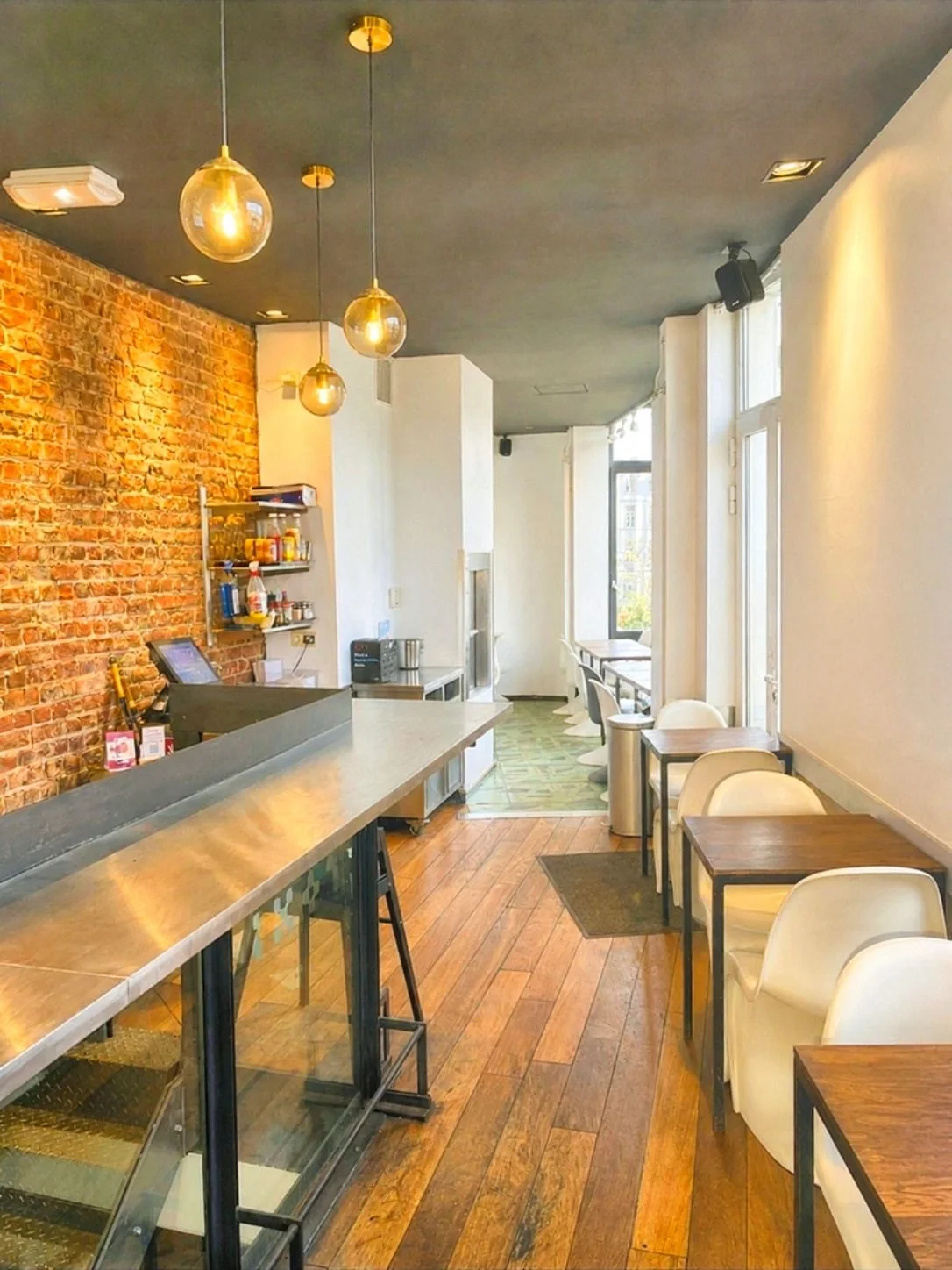 Intérieur du ROXI : mur de briques apparentes, comptoir en inox et suspensions dorées